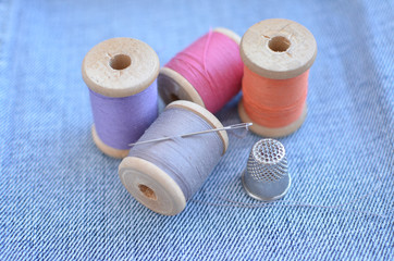 threads, needle, thimble on denim background