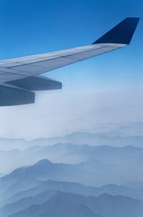 Fototapeta na wymiar Airplane wing above mountains in a fog