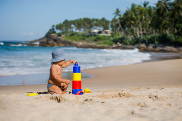 Kid plays with toys at the seashore in summertime