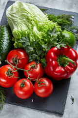 Bunch of fresh tomatoes with green leaves on stony board over white background, top view, close-up, selective focus