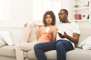 Obraz premium Surprised black couple watching TV at home