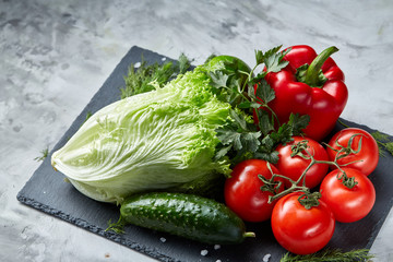 Bunch of fresh tomatoes with green leaves on stony board over white background, top view, close-up, selective focus