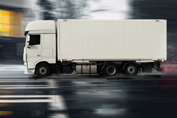 LKW fährt auf nasser Straße durch eine Stadt