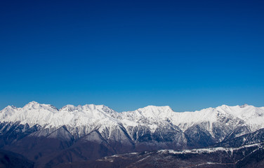 snow-covered mountains and forest against the blue sky