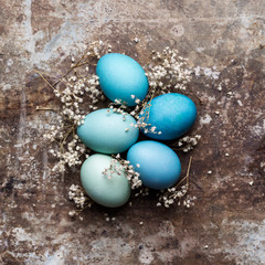 Fototapeta na wymiar Happy Easter rustic concept with copy space. DIY dyed various shades of blue Easter eggs on retro rusty metal background.
