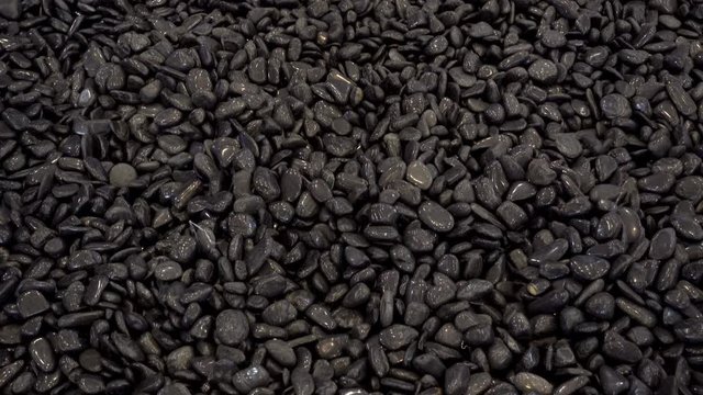 4K view of black pebble stones as a background approaching camera close-up.