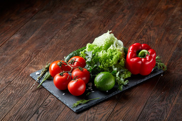 Close-up still life of assorted fresh vegetables and herbs on wooden rustic background, top view, selective focus.