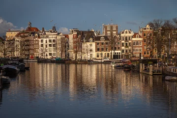 Papier Peint photo Lavable Canal water canals in Amsterdam with  traditional architecture reflecting in the water on a sunny day