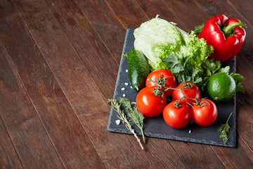Close-up still life of assorted fresh vegetables and herbs on wooden rustic background, top view, selective focus.