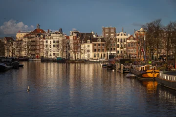 Papier Peint photo Canal water canals in Amsterdam with  traditional architecture reflecting in the water on a sunny day