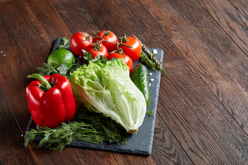Close-up still life of assorted fresh vegetables and herbs on wooden rustic background, top view, selective focus.