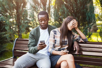 Woman sitting in park with man using smartphone