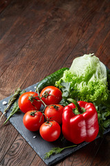 Close-up still life of assorted fresh vegetables and herbs on wooden rustic background, top view, selective focus.
