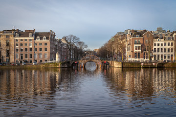 water canals in Amsterdam with a bridge in the middle and buildings on both of bridge's side 