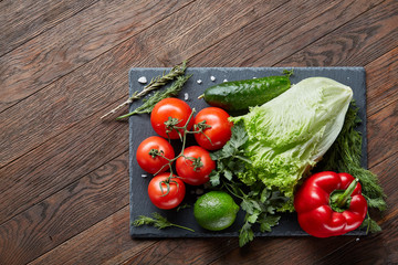 Close-up still life of assorted fresh vegetables and herbs on wooden rustic background, top view, selective focus.