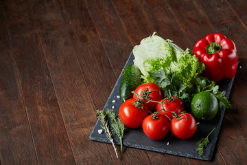 Close-up still life of assorted fresh vegetables and herbs on wooden rustic background, top view, selective focus.