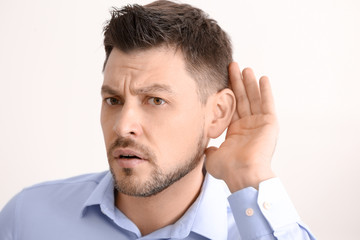 Obraz premium Mature man with hearing problem on light background