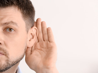 Mature man with hearing problem on light background