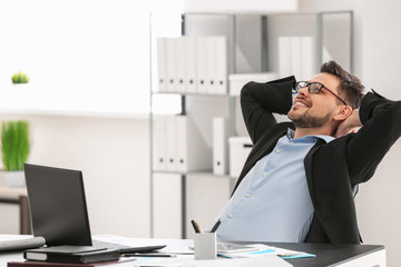 Handsome businessman relaxing in office - obrazy, fototapety, plakaty