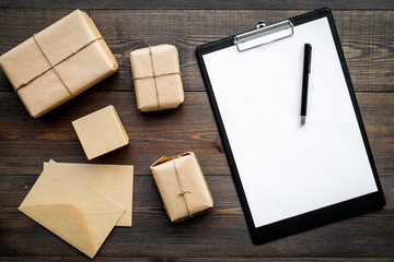 Courier workplace with cardboard box and letters for delivery on wooden background top view mockup