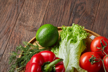 Close-up still life of assorted fresh vegetables and herbs on vintage wooden background, top view, selective focus.