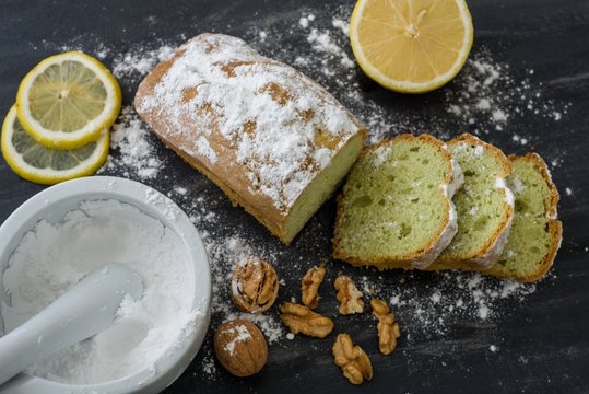 Mint cake on black surface with lemon, nuts, powdered sugar