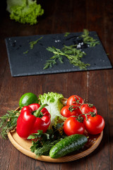Close-up still life of assorted fresh vegetables and herbs on vintage wooden background, top view, selective focus.