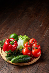 Close-up still life of assorted fresh vegetables and herbs on vintage wooden background, top view, selective focus.