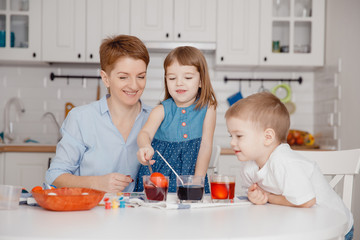 Easter. Happy family Mom and children son and daughter paint eggs with colors. Preparation for holiday.