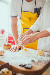 Male and female hands chef close-up, knead the dough, cook the dough on a kitchen.