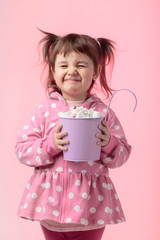 Cute little girl holding small violet bucket of marshmallow.