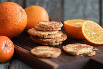 Healthy vegetarian snack. Homemade cookies and raw oranges on dark oak board