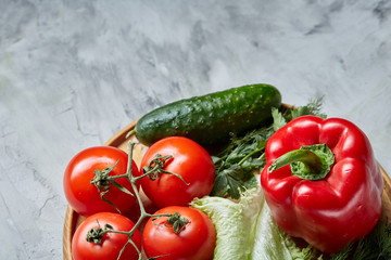 Still life of fresh organic vegetables on wooden plate over white background, selective focus, close-up