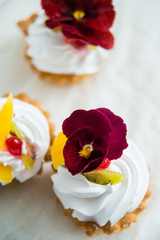 cake with fresh fruit and edible flowers Pansy Flowers on light background