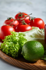 Still life of fresh organic vegetables on wooden plate over white background, selective focus, close-up