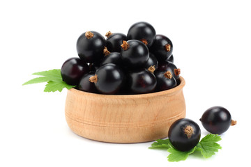 black currant in wooden bowl with green leaf isolated on white background