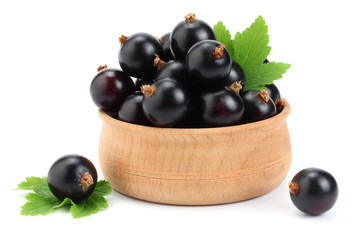 black currant in wooden bowl with green leaf isolated on white background