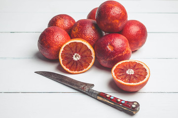 Blood oranges and knife on a white wooden background. Seasonal citrus fruit