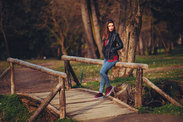 Portrait of a beautiful young woman in a leather jacket in the park