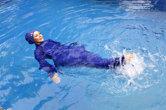 attractive woman in a Muslim swimwear  burkini swims in the pool