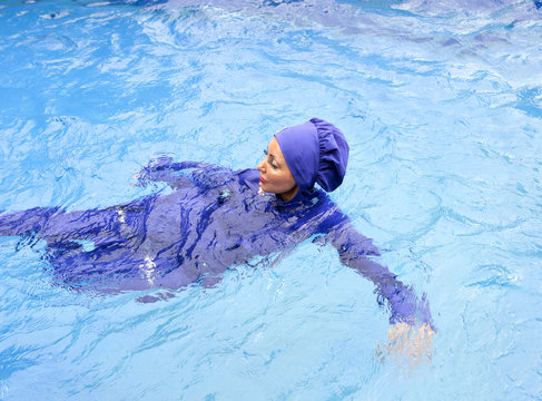 attractive woman in a Muslim swimwear  burkini swims in the pool