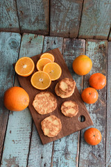 Healthy vegetarian snack. Homemade cookies, raw clementines and oranges on cutting board on shabby blue background top view copyspace