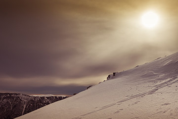 Snowy slope with mountain and pale sun in the background, Belluno, Veneto, Italy