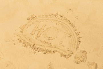 Word - hot, written on the sand, top view. Summer background