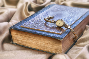 Vintage old clock lying on book .