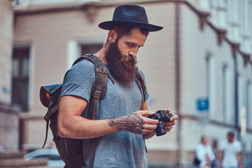 A handsome hipster male with a stylish beard and tattoo on his arms dressed in casual clothes,...
