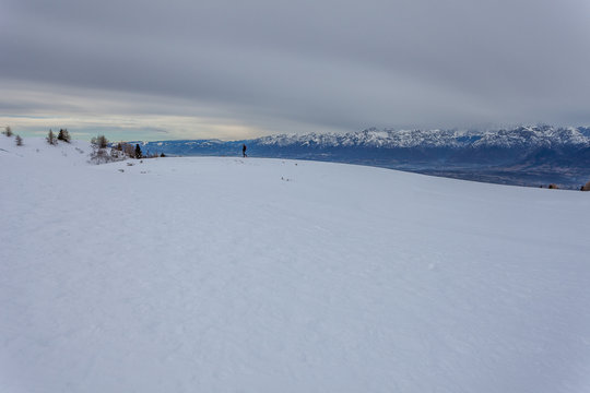 Man walking on snow, with the Dolomite peaks in the background, Col Visentin, Belluno, Italy
