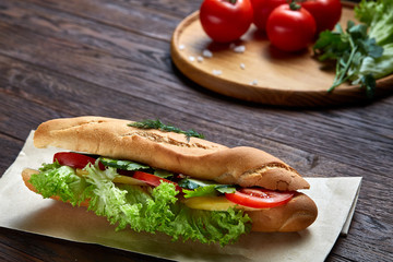 Fresh and tasty sandwich with cheese and vegetables on paper napkin over wooden background, selective focus, top view
