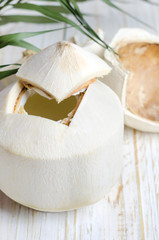 Young coconut on white wooden background. © devmarya