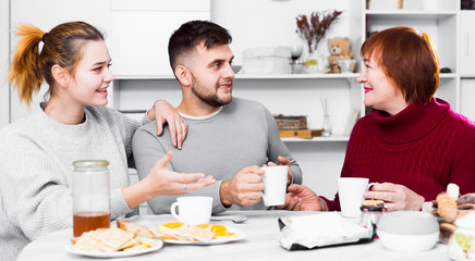 Cheerful elderly mother with adult children drinking tea